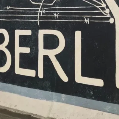 Muro de Berlín con grafiti icónico y viajero en primer plano