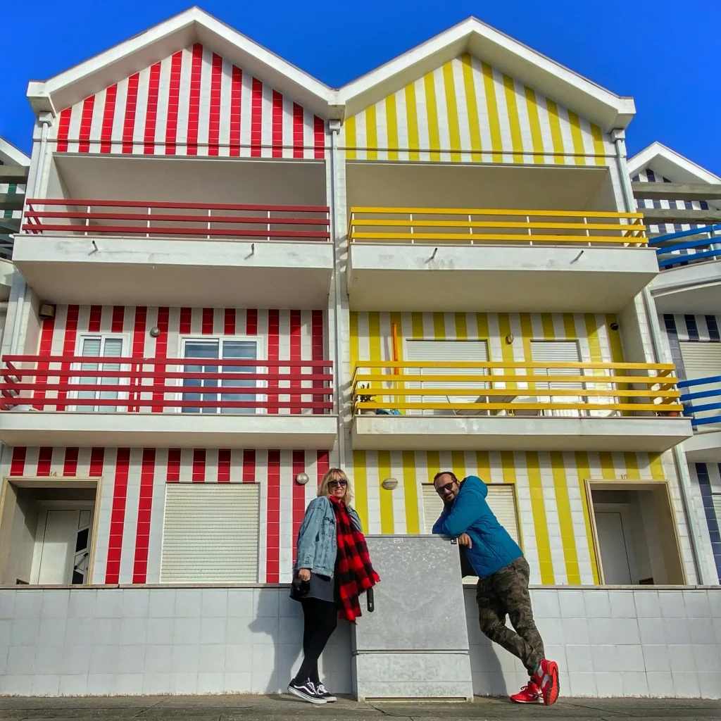 Casas de colores en Portugal con pareja viajera frente a fachadas rayadas