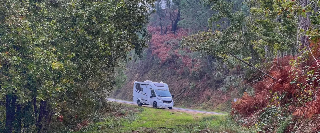 Autocaravana en una carretera entre bosques de Galicia durante una ruta en autocaravana
