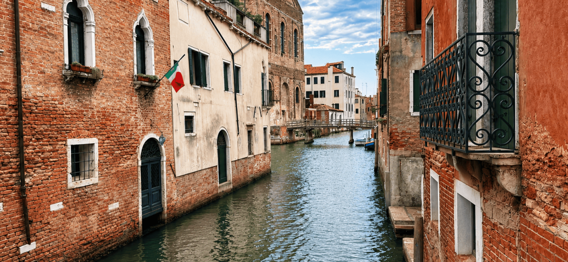 Canal típico del centro histórico de Venecia con edificios tradicionales y un puente al fondo