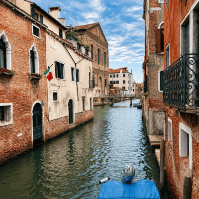 Canal típico del centro histórico de Venecia con edificios tradicionales y un puente al fondo