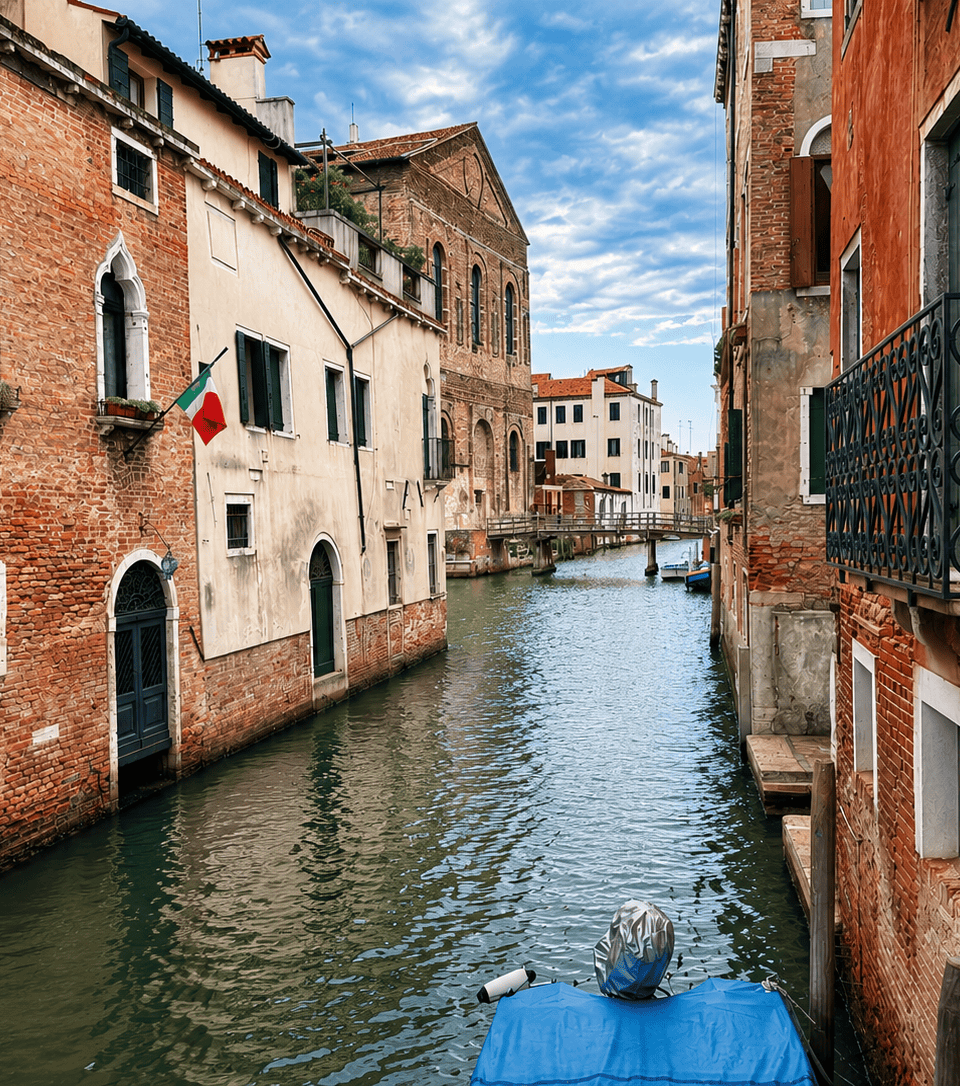 Canal típico del centro histórico de Venecia con edificios tradicionales y un puente al fondo