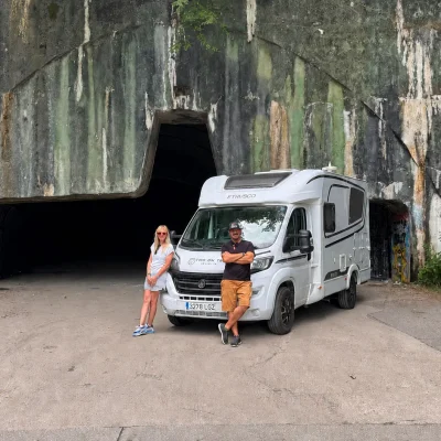 Two On Trip con su autocaravana ante una entrada de la base aérea de Željava